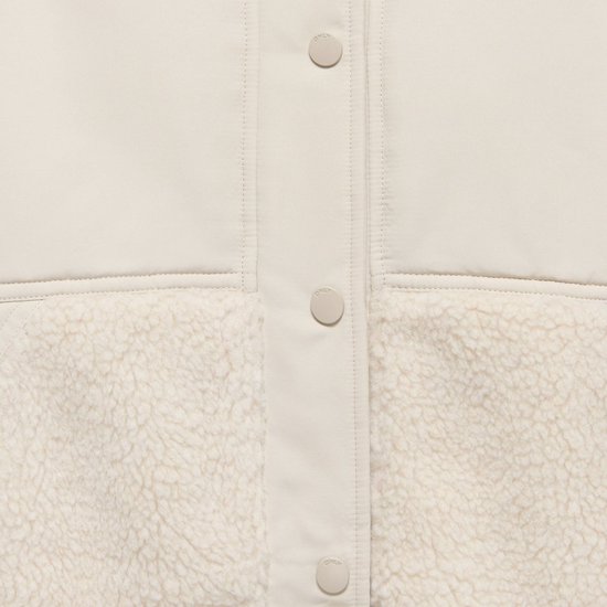 Sluiting met knopen van een beige jas met teddy-inzet.