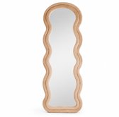 Een taupe beige staande spiegel met een golvend, gestoffeerd frame van suède fluweel. De spiegel is lang en smal.
