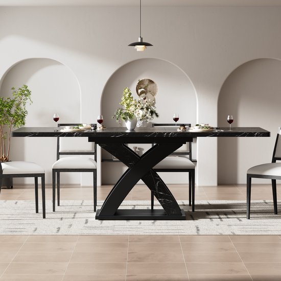Zwarte eettafel met marmerlook, X-vormig onderstel, zes witte stoelen.