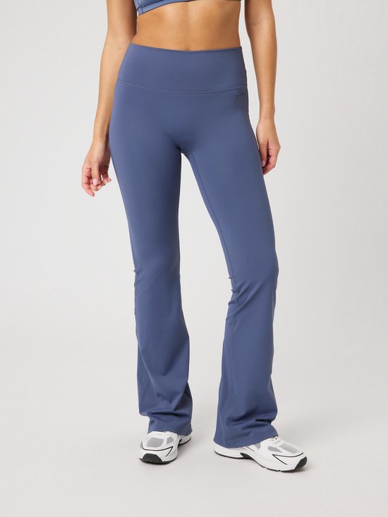 Mannequin portant un pantalon de sport bleu à jambes larges et des baskets blanches.