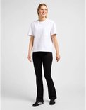 Vrouw in een zwarte Lee spijkerbroek met uitlopende pijpen en een witte t-shirt met borstzak.