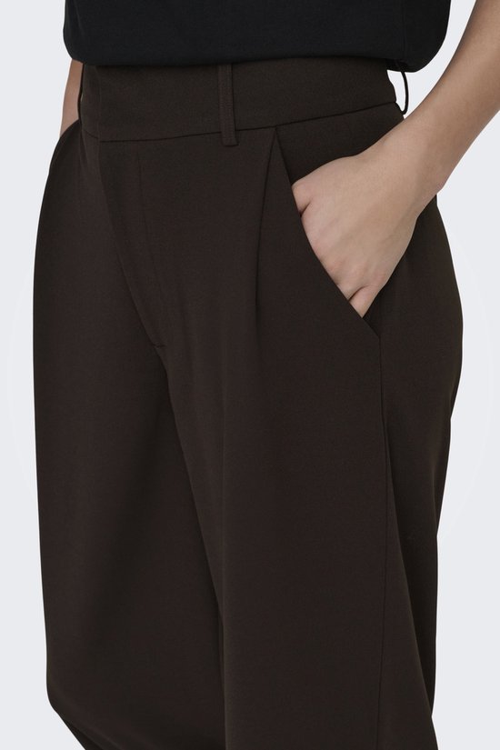 Detail van de donkerbruine wijde broek met broekzakken.