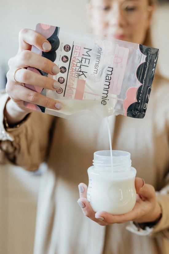 Vrouw giet melk uit een "mammie" melk bewaarzakje in een babyflesje.