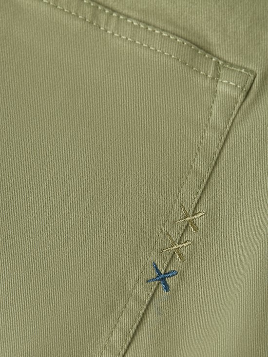 Detail van de achterzak van een olijfgroene chino met geborduurde details.