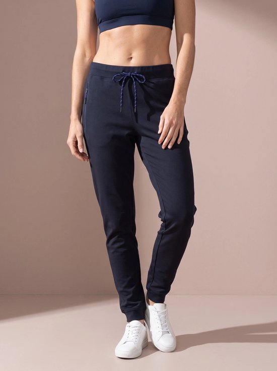 Model draagt donkerblauwe sportbroek met koordjes en witte sneakers.
