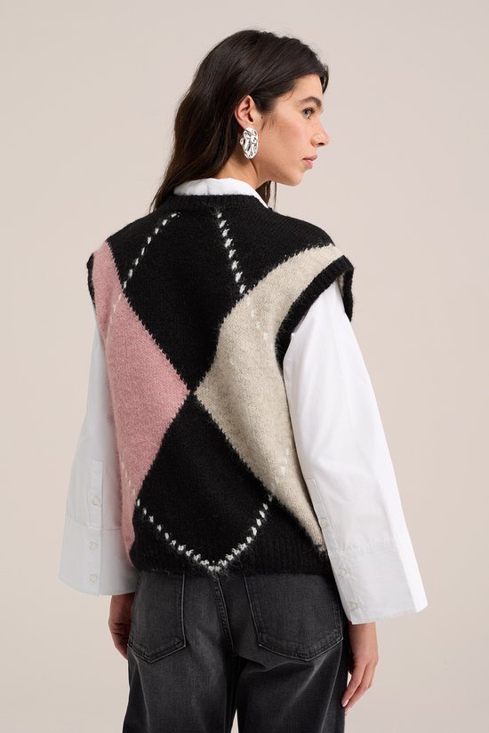 Achterkant van model die een gebreide spencer draagt met ruitpatroon in zwart, roze en beige.