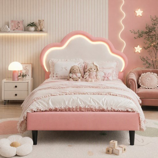 Roze kinderbed met een wolk-vormig hoofdbord met LED-verlichting. Dekbed met kant en strikken, twee knuffels en kussens.