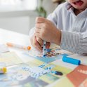 Kind gebruikt blauwe stempelstift op een Bluey kaart, met vader op de achtergrond.