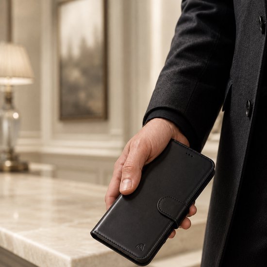Man in een grijs jasje houdt een gesloten zwarte leren telefoonhoes vast.