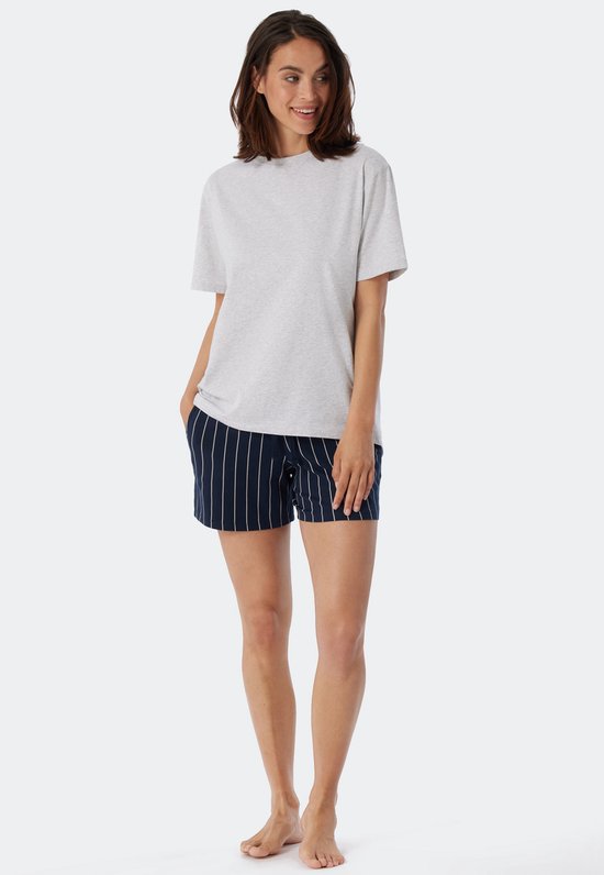 Un mannequin porte un t-shirt gris chiné à manches courtes et col rond, les mains dans les poches d'un short rayé.