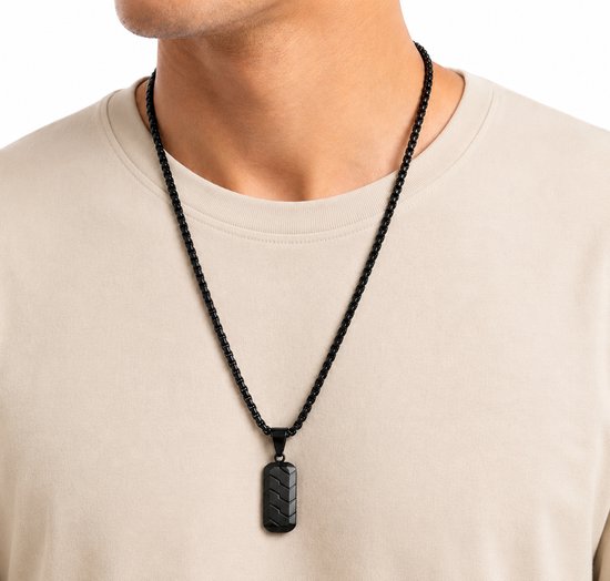 Close-up van een man die een zwart T-shirt draagt met een zwarte schakelketting.