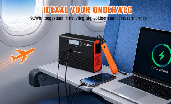 Zwarte draagbare powerstation met oranje lus, op een vliegtuigtafeltje. Laptop en telefoon worden opgeladen.