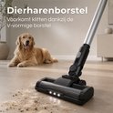 Close-up van een zwarte steelstofzuigerkop met V-vormige borstel die dierenharen opzuigt van een houten vloer. Een Golden Retriever ligt op de achtergrond. "Dierenharenborstel Voorkomt klitten dankzij de V-vormige borstel".