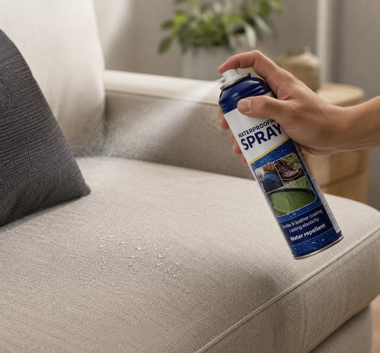 Hand spuit bus met 'WATERPROOF SPRAY' op een lichte stoffen bank, water druppelt op de stof.