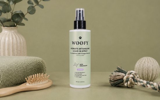 WØØFY Hydrate Detangling Leave-In Spray met lavendel voor honden, naast een handdoek, borstel en decoratie.