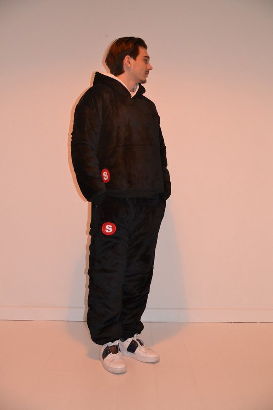 Zwarte oversized hoodie en joggingbroek met rode 'S' logo's. Model draagt witte sneakers.