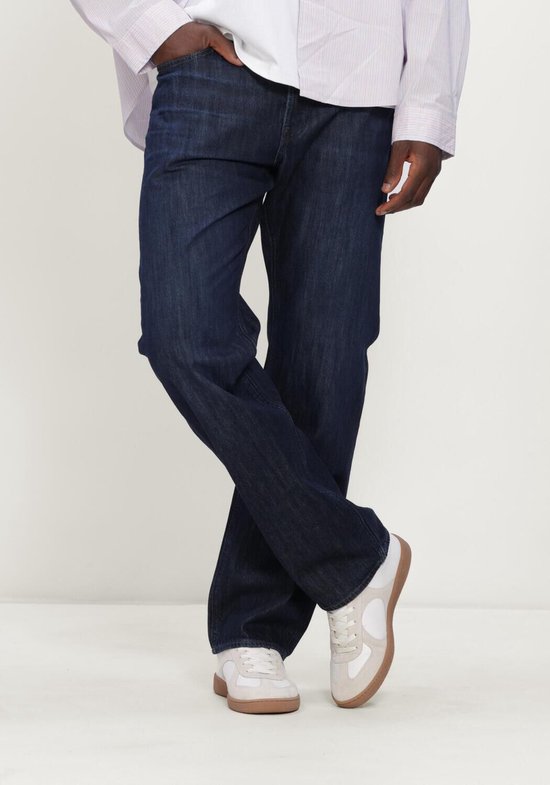Model draagt een donkerblauwe regular straight jeans van G-Star Raw. De broek heeft een casual uitstraling met witte sneakers.