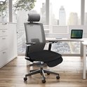 Zwart autostoelkussen op een ergonomische bureaustoel in een modern kantoor.