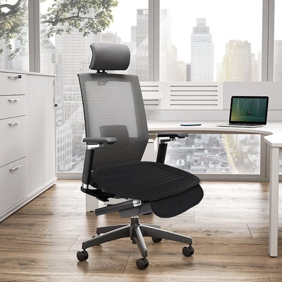 Zwart autostoelkussen op een ergonomische bureaustoel in een modern kantoor.