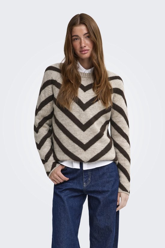 Lichtbruine trui met donkerbruine chevronprint, gedragen door een model met een witte blouse en jeans.
