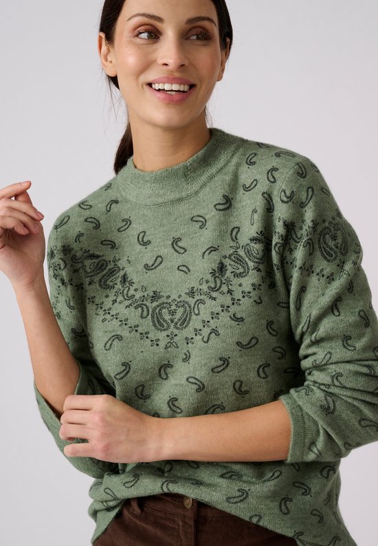 Model draagt een groene gebreide trui met paisley-print en opstaande kraag.