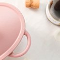Roze gietijzeren braadpan in hartvorm met handvatten, detail van het deksel.