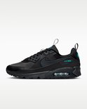 Zijaanzicht van een zwarte Nike Air Max 90 sneaker met turquoise 'AIR MAX'-opschrift en luchtkussentjes.