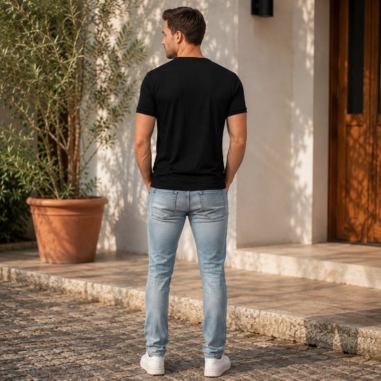 Man met donker haar, draagt zwarte t-shirt en lichtblauwe jeans, staat buiten.