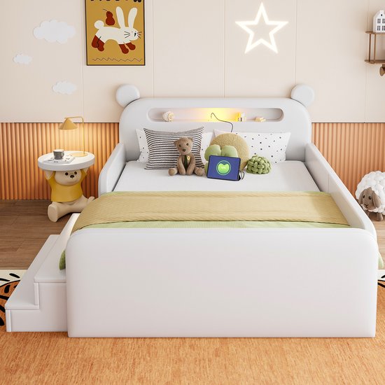 Wit kinderbed met berenoren, nachtkastje met lade en geïntegreerde nachtlamp, decoratie van schilderij, sterlicht en teddybeer.