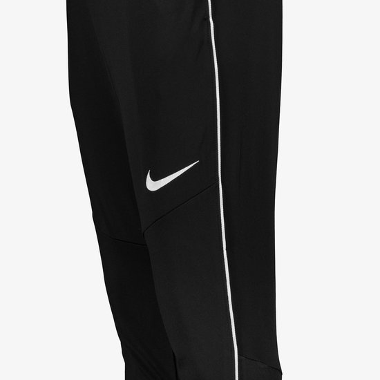 Detail van een zwarte Nike trainingsbroek met wit Nike logo en bies.
