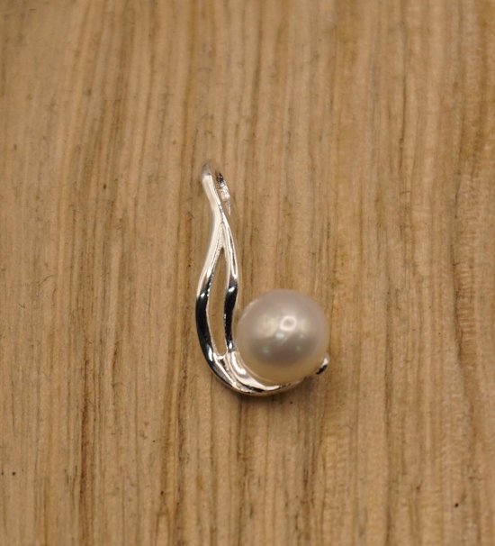 Zilveren hanger met een gedraaide vorm en een witte zoetwaterparel op een houten achtergrond.