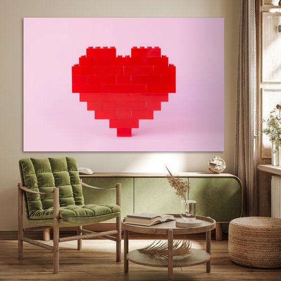 Rood hart van bouwblokken op een roze achtergrond, in een woonkamer met een groene stoel.