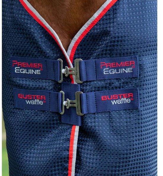 Donkerblauwe paardendeken met rode en witte bies. Twee sluitingen met 'Premier Equine' en 'Buster waffle' logo's.
