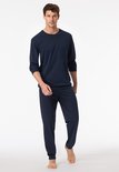 Man draagt een donkerblauwe pyjama met verticale strepen en effen donkerblauwe broek.