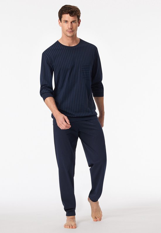 Man draagt een donkerblauwe pyjama met verticale strepen en effen donkerblauwe broek.