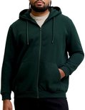 Man met dreadlocks in open donkergroene hoodie, beige T-shirt en zwarte broek.