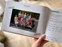 Klasfoto van 13 kinderen en een juf buiten. De kinderen staan en zitten in groepen. Tekst: 'OBS De Zonnewei 2025-2026 Groep 1-2c'.