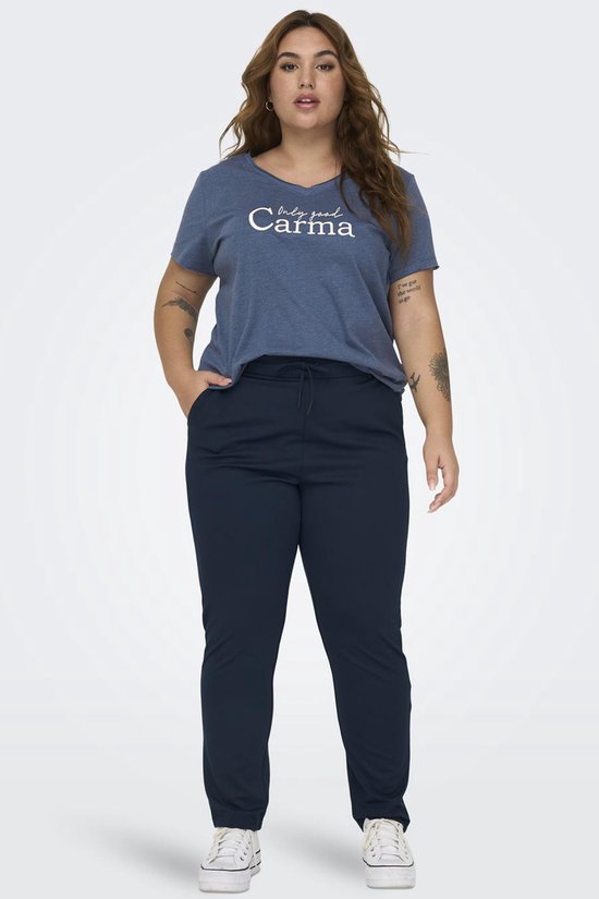 Model in donkerblauwe broek, blauw T-shirt met tekst en witte sneakers.