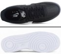 Bovenkant en onderkant van een zwarte leren Nike Air Force 1 sneaker met witte zool.
