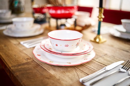 Wit dinerbord met rode rand en kerstprintjes, gestapeld met kleinere borden en een kom.