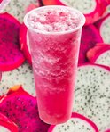 Roze drakenvruchten smoothie met schuim, omringd door gesneden drakenvruchten.