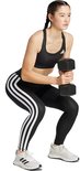Model in zwarte legging met witte Adidas strepen maakt een squat met een dumbbell
