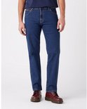 Man draagt een donkerblauwe jeans met bruine stiksels en donkerrode schoenen.