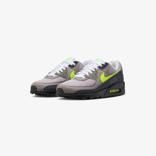 Grijze Nike Air Max 90 sneakers met neon groene swoosh, witte veters en zwarte zolen.