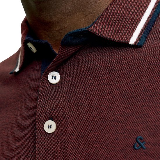 Close-up van bordeauxrode polo met witte en marine boorden aan de kraag en witte knopen.