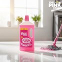 Fles The Pink Stuff vloerreiniger en een roze mop met roze vloeistof op een lichte tegelvloer.