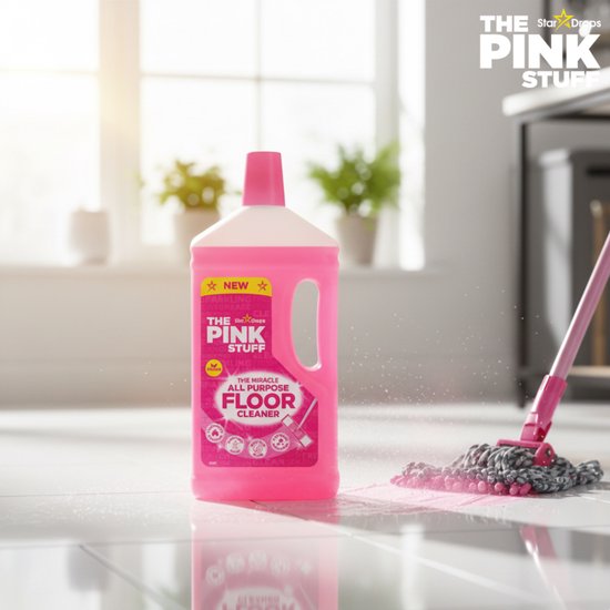 Fles The Pink Stuff vloerreiniger en een roze mop met roze vloeistof op een lichte tegelvloer.
