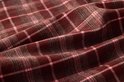 Gedetailleerde close-up van bordeauxrode stof met smalle roze en bruine ruiten.