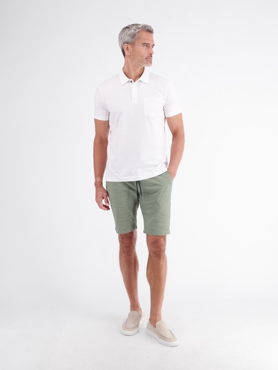 Man met grijze haren, staand in witte polo en groene chino shorts met trekkoord.