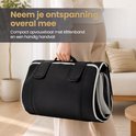 Persoon draagt opgevouwen zwarte massagemat met handvat. "Neem je ontspanning overal mee".